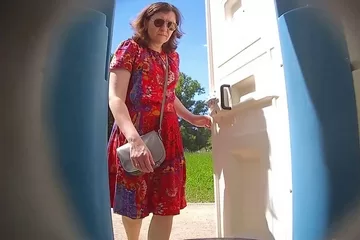 Зрелая женщина писает в кабинке летнего туалета